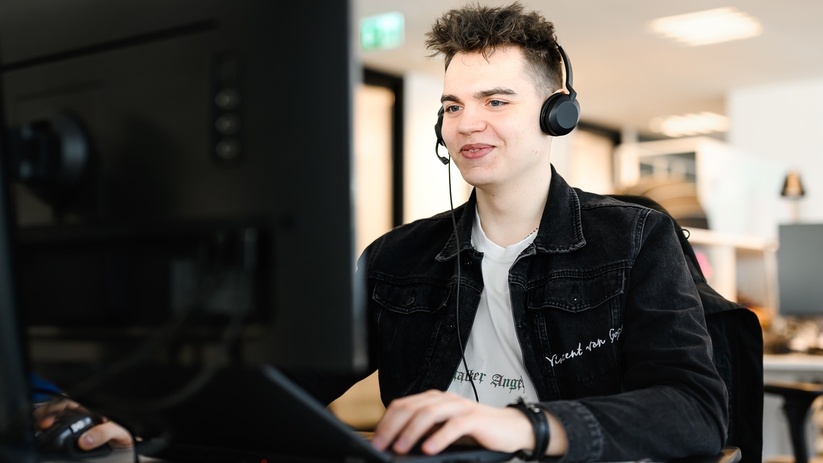 Young male worker sitting in front of computer and smiling