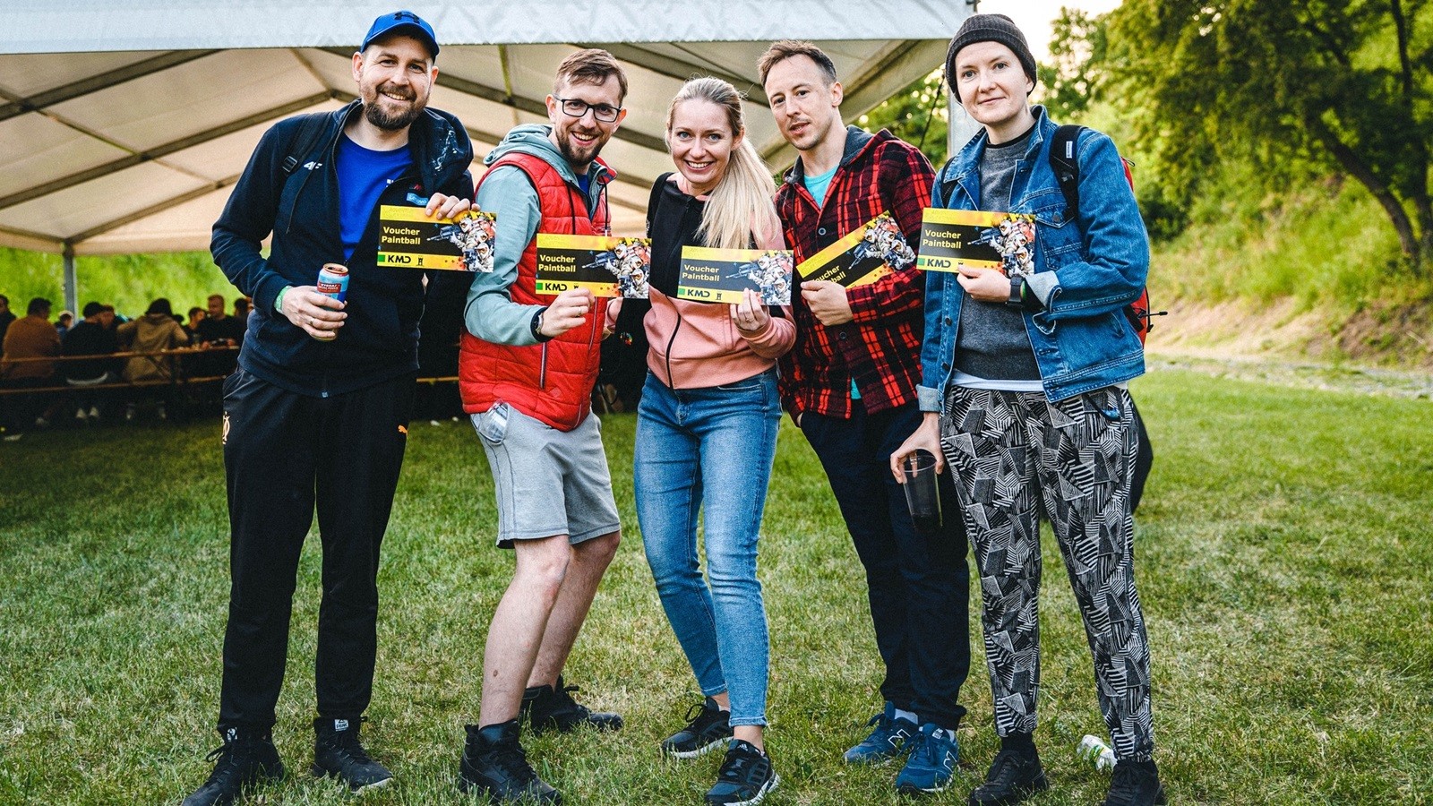 Five KMD Poland employees holding up vouchers for a paintball event